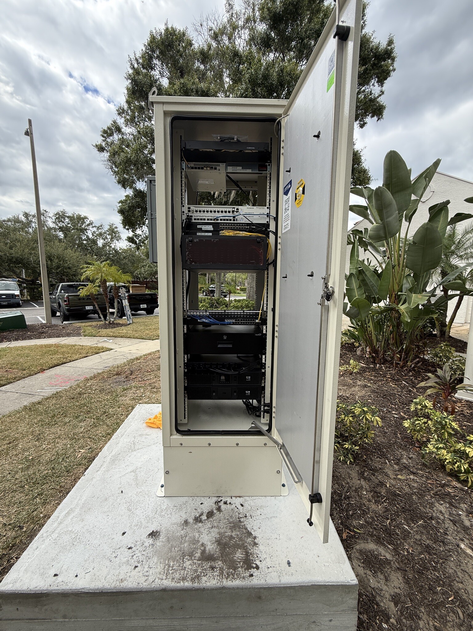 Open exterior telecommunications cabinet with installed network and power equipment